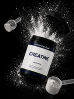 Pump The Fuel Creatine Monohydrate powder dramatic black background with powder burst explosion, open tub tilted with two measuring scoops