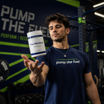 Athlete holding Pump The Fuel Tropical Sunrise pre-workout supplement in a strength training gym